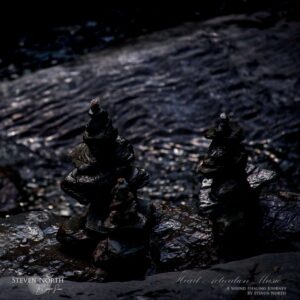 Two balanced meditation stones on a dark, reflective water surface, symbolizing focus and tranquility for deep meditation practices.